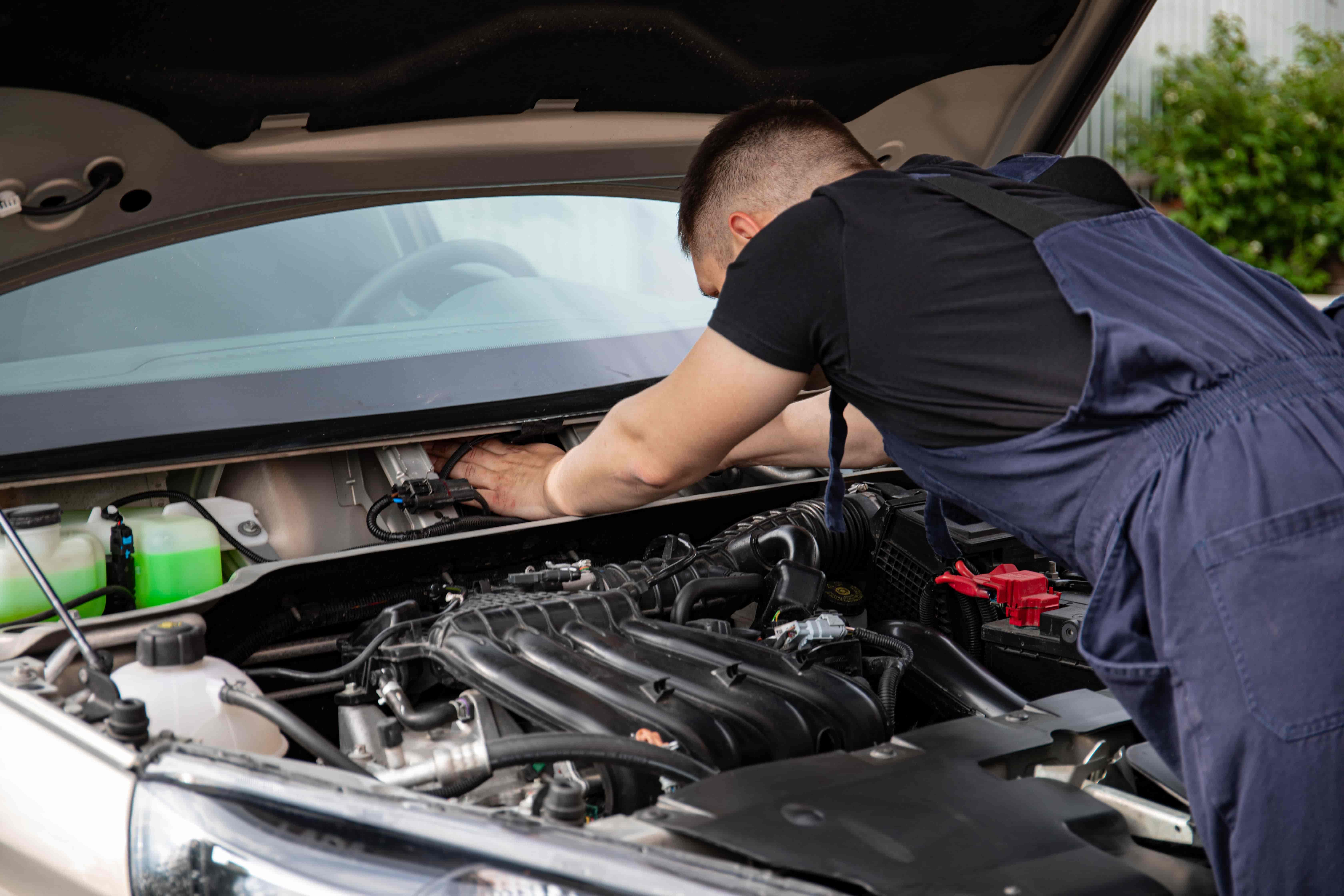 Mechanic inspecting a used car exterior with a checklist
